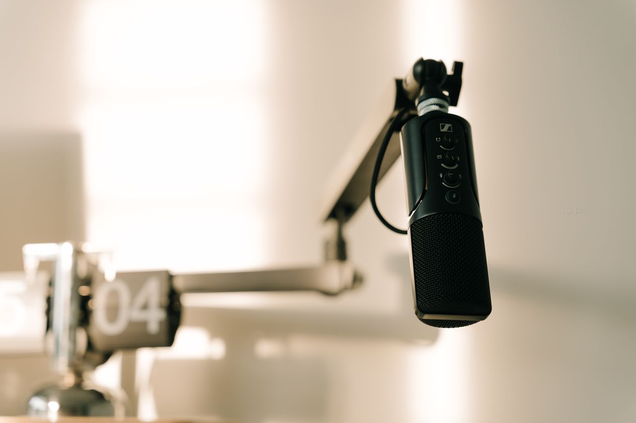 about-img-01 A sleek professional microphone on a boom arm in a minimalist studio.