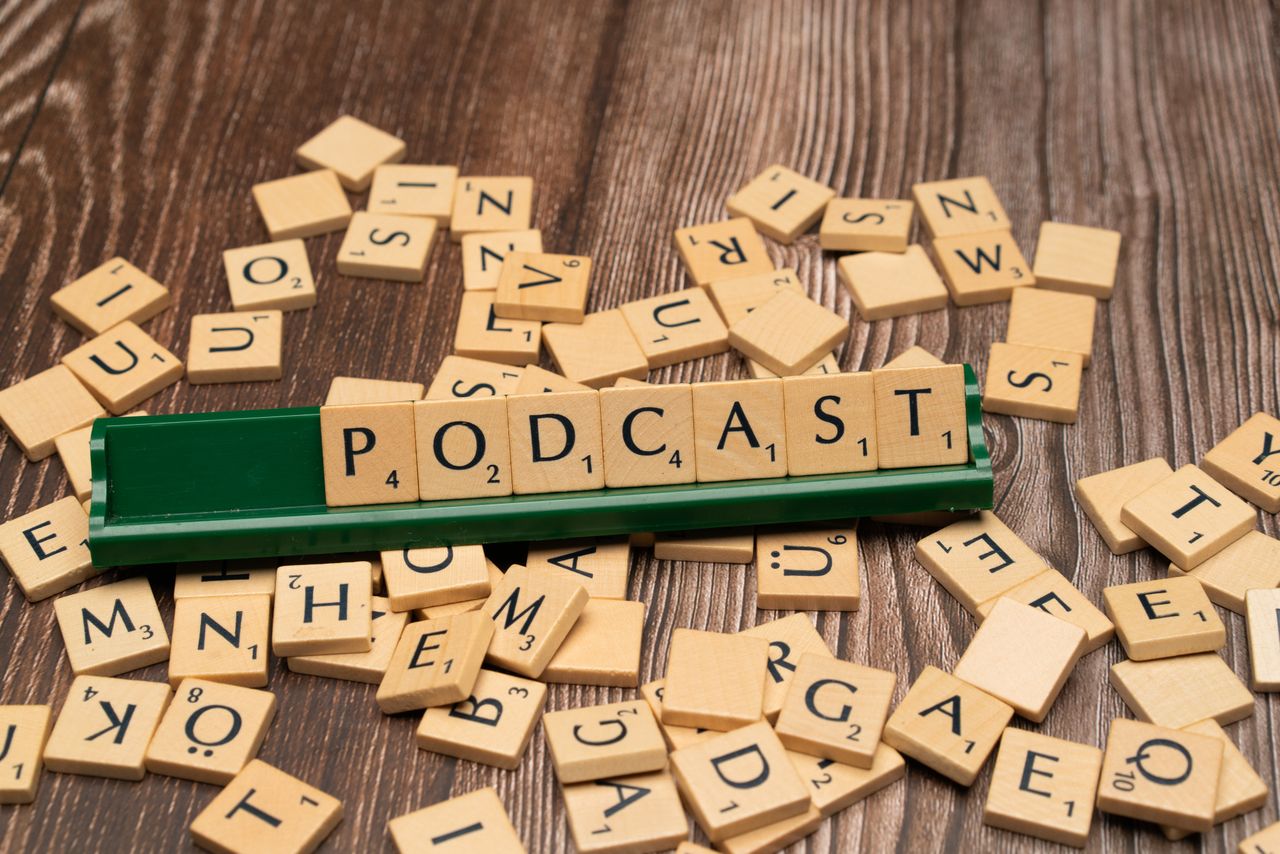 gallery-03 Wooden letter tiles on a board spelling the word Podcast, symbolizing digital media and creativity.
